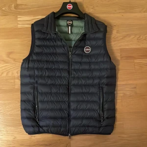 Mörkblå dunväst från Colmar - Tja säljer nu min mörkblå dunväst från colmar den har dragkedja framtill. Västen har två praktiska fickor med dragkedja och klassisk Colmar-logga på bröstet. Insidan är ljusgrön och materialet är lätt och smidigt – perfekt nu till höstväder 🍂🍁