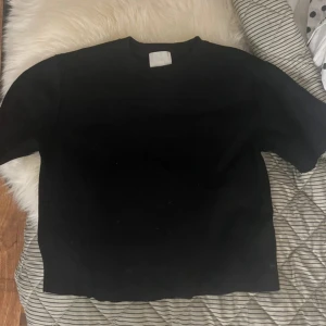 Svart tröja från H&M i bomull XS - En basic svart tröja från H&M i storlek XS. Tröjan har rund halsringning, raka ärmar och är gjord i mjuk bomull. Perfekt att styla med jeans eller kjol för en clean look.