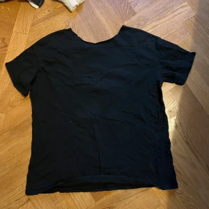 Svart basic t-shirt i bomull - Enkel svart t-shirt med rund hals och korta ärmar. Tillverkad i mjuk bomull, perfekt för en clean och stilren look. Passar till allt och är ett måste i garderoben.