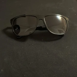 Svarta Carrera solglasögon - Snygga svarta solglasögon från Carrera med rektangulär form och coola bikakemönstrade skalmar. Glasögonen har mörka linser och en sportig vibe som passar perfekt till sommaren. Liknar Rayban Boyfriend väldigt mycket. Pris kan sänkas vid snabb affär