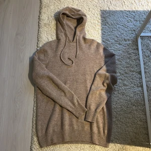 Beige hoodie från Ventuno i ullmix Kashmir. - Säljer en beige hoodie från Ventuno i mjuk ullmix/kashmir. Tröjan har huva med snörning och ribbade muddar vid ärmslut och nederkant. Perfekt för dig som gillar en clean och stilren look.🤩 Passformen är normal. Bara att höra av vid frågor och funderingar.😊