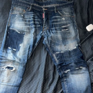 Dsquared2 Cool Guy jeans blå, stl 50 - Säljer ett par Dsquared2 Cool Guy jeans i blå tvätt med slitningar, patchwork och tryckt bakficka. Jeansen har fem fickor, låg midja och raka ben. Materialet är klassisk denim i bomull. Snygga detaljer och streetkänsla. Äkta.