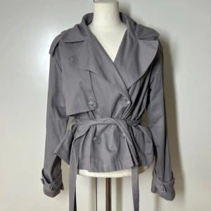 Kort trenchcoat Gina tricot  -  Superfin trenchcoat med snöre från Gina. Storlek s. Nypris 700kr, slutsåld.  Köp sker via köp nu, jag postar inom 24h. Kvar tills markerad såld