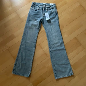 Y2K ljusblå jeans med bootcut från Gina Tricot - Säljer ett par ljusblå jeans i storlek 32 från Gina Tricot. Jeansen har klassisk femficksdesign, snygga ficklock med knappar bak och bootcut-ben. Materialet är jeans i bomull och passformen är normal. Perfekta för dig som gillar retrovibbar och stilren denim.