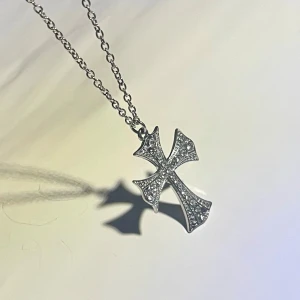 Vintage 90-talshalsband- Sif Jakobs (Ponza)- Strasskors - Säljer ett mycket fint vintagehalsband från slutet av 1990-talet, ursprungligen från den kända danska smyckesdesignern Sif Jakobs och deras Ponza-kollektion. Detta halsband är i mycket bra, nästintill oanvänt skick. Korset är elegant utformat och täckt av små, glittrande stenar som ger en exklusiv känsla. Det är tillverkat av Silverpläterad metall och själva korset är täckt av strass/ zirkoner. Mått: L 66 cm (kedja) L 4 cm (kors) Total vikt 6,9 gram