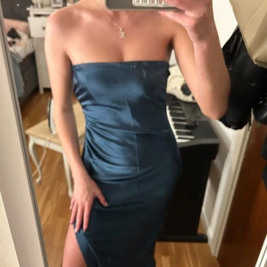 Zara satinklänning Mörkblå med slits - Säljer en elegant Zara mörkblå långklänning i satin med figurnära passform. Klänningen har avtagbara tunna axelband och kan bäras både axelbandslös och med band. Den har en snygg slits framtill och en stilren, minimalistisk look.
