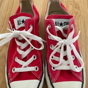 Röda Converse All Star sneakers - Säljer ett par klassiska röda Converse All Star sneakers med vita snören. I storleken 36,5. Är i fint skick har en liten svart fläck på sig
