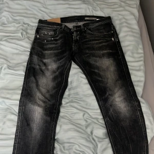 Svarta skinny jeans från George - Säljer ett par svarta skinny fit dond up jeans från George med slitna detaljer och snygg tvätt. Jeansen har klassisk femficksdesign, dragkedja och knapp framtill. 
