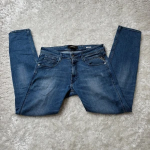 Blå Replay Anbass jeans - Snygga blå Replay Anbass jeans i klassisk femficksmodell. Jeansen har en rak passform med lätt slitning framtill och bakfickor med diskret broderi. Köptes nya från pondus men kommer inte längre till användning, bra skick men kan finnas något märke på slitage.