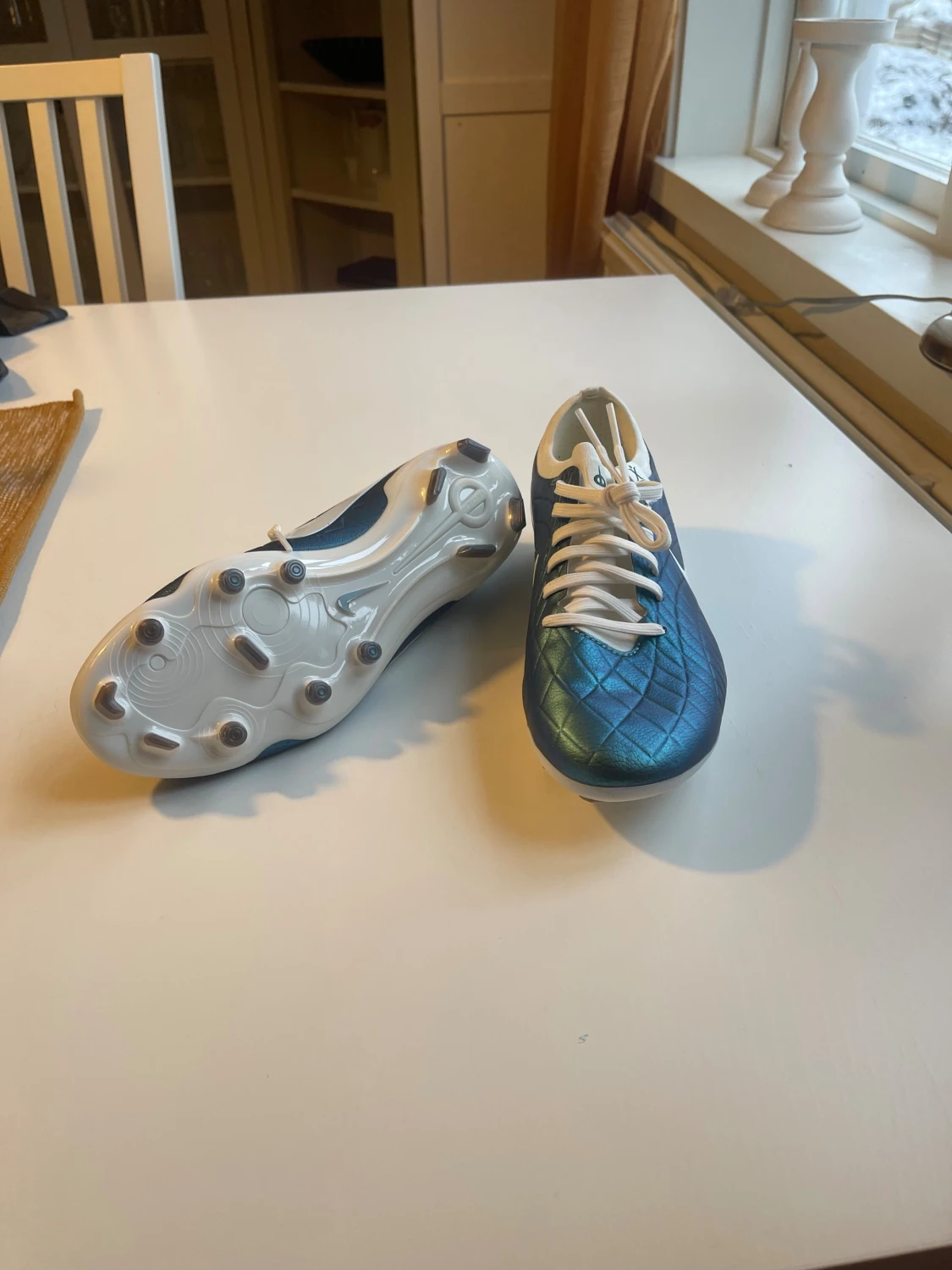 Detta är en fotbollssko av modellen Nike Tiempo Legend 10 Elite FG i en blå/grön iriserande färgvariant.