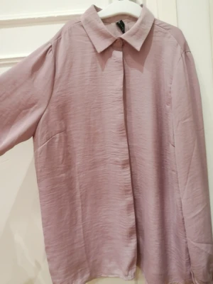 Ljuslila skjorta med knytärm - Säljer en ljuslila skjorta från Bik Bok med snygg krage och knappar framtill. Skjortan har långa ärmar med coola knyt- och rynkdetaljer vid mudden. Materialet är mjukt och har en lätt skrynklig struktur som ger en chill vibe. Den är i stl xs, men sitter som s. Den är aldrig använd. Köptes på New Yorker men användes aldrig. 😊