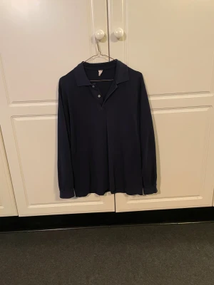 Mörkblå pikétröja - Säljer denna mörkblåa pikétröjan i storlek M. Har inte koll på vilket märke det är, ser ut som att det kan heta typ ”Star”, men den är i alla fall gjord i Finland. Jag har därför inte heller koll på nypris. Den är i rätt använt skick och den understa knappen har oftast problem att knäppas. Hör av er vid eventuella funderingar!