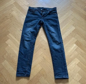 Levi's 512 mörkblå jeans W29 L32 - Snygga Levi's 512 jeans i mörkblå tvätt med klassisk femficksdesign och smal passform. Jeansen har raka ben, knapp och dragkedja fram samt brunt läderpatch bak i midjan. Perfekta för dig som gillar stilrena och tidlösa jeans. skriv vid frågor eller funderingar 
