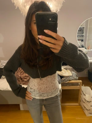 Mörkgrå croppad stickad kofta - Säljer en mörkgrå croppad stickad kofta med dragkedja framtill. Koftan har långa ärmar och är ribbstickad för en cool och avslappnad look. Perfekt att slänga över ett linne eller en topp för en trendig outfit. Från weekday! ❤️ aldrig använd