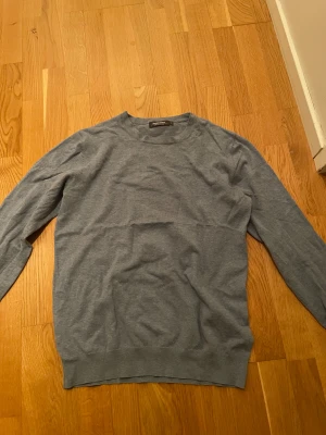 Blå långärmad tröja Dressmann M - Superskön grå långärmad tröja från Dressmann i mjuk Supima bomull. Enkel och stilren design med rund hals och ribbade muddar. Perfekt för dig som gillar basic och vill ha en tröja som funkar till allt. Snygg passform och lätt att matcha med jeans eller chinos.