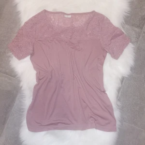 Rosa topp från Jacqueline de Yong, storlek S - Supersöt ljusrosa blus från Jacqueline de Yong med korta ärmar och vacker spets upptill. Blusen har rund halsringning och är tillverkad i mjukt material som känns skönt mot huden. Perfekt för dig som gillar romantiska detaljer och en feminin look. Är i fint använt skick. Storlek S