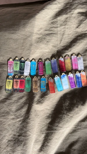 Färgglada Monster & Red Bull berlockhängen - Samling med 24 unika berlockhängen formade som Monster och Red Bull burkar. Hängena är i olika färger som blå, rosa, grön, gul, röd, lila och orange. Perfekta till halsband, armband eller nyckelringar för dig som gillar energidrycksvibbar och färgstark stil. Även perfekt om du vill göra din egna adventskalender! 24st luckor!