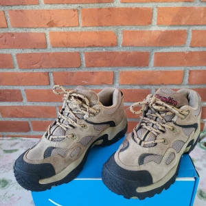 Beige sneakers från Brolin strl 37 - Säljer ett par chunky sneakers från Brolin i beige mocka och mesh med svarta detaljer. Skorna har grov sula, snörning och broderad logga baktill. Perfekta för dig som gillar outdoor-vibe och vill ha något tåligt och snyggt till vardags.