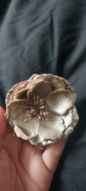 Guldig blomformad brosch/hårklämma - Snygg blomformad accessoar i guldigt tyg med realistiska kronblad och detaljerad mitt. Kan användas både som brosch och hårklämma tack vare dubbla fästen på baksidan. Perfekt för att ge din outfit en unik och elegant touch.