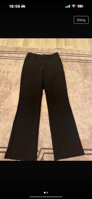 Svarta wide kostymbyxor Bik Bok - Svarta kostymbyxor från Bik Bok i storlek 36. Byxorna har en klassisk wide passform med raka, vida ben och bälteshällor i midjan. Snyggt stilrena och passar perfekt till en trendig look. Materialet känns mjukt och har en lätt stretch.