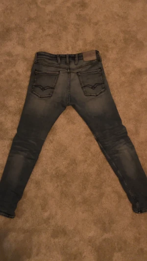Replay Jeans - Säljer ett par Replay Anbass jeans i skinny fit med snygg tvättad blå färg. Klassisk femficksmodell med detaljerade bakfickor och logopatch i midjan. Jeansen har låg till medelhög midja och är gjorda i stretchigt denim för skön passform. De är i ganska bra skick och redo för nästa användare!🥰 Storlek 30/32