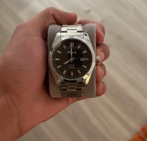 Silverfärgad  Quartz klocka från Doventi  - Stilren klocka från Doventi med svart urtavla och silverfärgat armband i metall. Klockan har datumvisning och klassiska indexmarkeringar. Quartz-urverk och rund boett ger en tidlös look som passar perfekt på handleden.