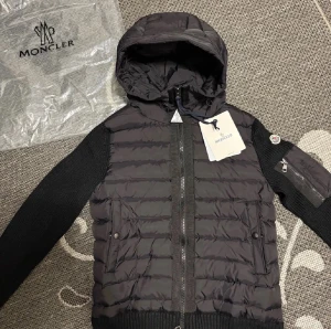 Svart Moncler pufferjacka med huva - Snygg svart pufferjacka från Moncler med stickade ärmar och vadderad kropp. Bästa priserna här på Plick och skicka gärna in bud då jag kan sänka priset vid snabb affär.