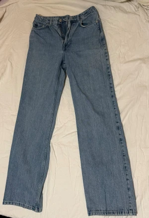 Weekday Rowe extra high straight jeans - Säljer ett par Weekday Rowe extra high straight jeans i klassisk blå tvätt. Jeansen har hög midja, raka ben och fem fickor. Materialet är robust denim i bomull och passformen är relaxed med en snygg vintagekänsla. W28/L32