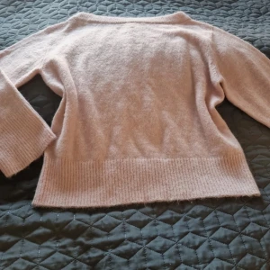 Ljusrosa stickad tröja med bred mudd - Supermjuk ljusrosa stickad tröja med bred ribbad mudd nertill och vid ärmsluten. Tröjan har en enkel, klassisk design med lång ärm och rund hals. Perfekt för lager-på-lager under kyliga dagar. Storlek 170. Använd en gång. 