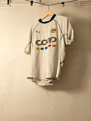 Hammarby - matchtröja säsongen 2002 - Säljer en vit Hammarby fotbollströja från Puma med gröna detaljer och klubbmärke på bröstet. Varit med i över 20 år.