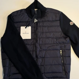 Navy Blå Moncler Cardigan - Navy Blå Moncler Cardigan. Storlek L/3 men sitter mindre i storleken så även rekommenderad för M. Skick 10/10. Vårt pris: 1899kr. Tag och lappen är också av till skillnad från bilderna.