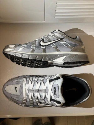 Nike P-6000 sneakers - Nike P-6000 Sneakers i silver, grå och vit med svarta detaljer.  Köpte för 1400kr 