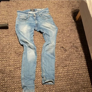 Replay ljusblå jeans slim fit  - Säljer ett par ljusblå jeans från Replay med klassisk femficksdesign och snygga slitningar. Jeansen har smal passform och normal midja, tillverkade i mjukt denimtyg för en bekväm känsla. Perfekta för dig som gillar en stilren och avslappnad look. Storleken är W31 L32. Tänk inte ens tanken på att inte höra av dig om du har några frågor!😁 Mötet sker endast i Stockholm btw👍