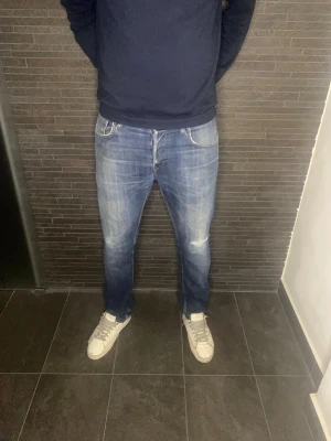 Blå Lee Daren jeans - Säljer ett par klassiska Lee Daren jeans i blå tvätt med snygga slitningar och kontrastsömmar. Nästan aldrig använda och därav i mycket fint skick! Nypris:1100