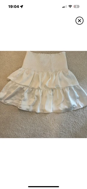 Neo Noir kjol  - Vit minivolangkjol från Neo Noir i storlek S. Har en liten fläck men syns inte tydligt. Nypris 599kr. Kan gå ner i pris vid snabb affär.