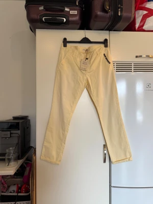 Beige byxor från Odd Molly med knappar - Snygga gula chinos från Odd Molly med dekorativa knappar på ena sidan och snörning i midjan. Modellen har raka ben och är tillverkad i mjukt bomullsmaterial. Perfekt för dig som gillar en clean och chill stil med unika detaljer. Från märket Odd Molly. Storlek 3 som enligt deras storleksguide motsvarar en L. Helt nya med tags. Men jag tycker att de är något ”bleka” på vissa ställen. Eller om de bara är så naturligt. 