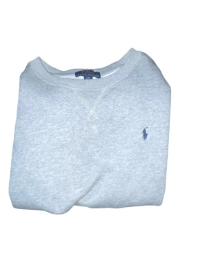Grå sweatshirt från Polo Ralph Lauren - Klassisk grå sweatshirt från Polo Ralph Lauren med rund halsringning och broderad logga vid bröstet priset är inte hugget i sten. 