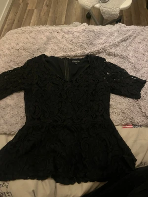 Svart spetsblus från Stockh LM - Säljer en svart blus från Stockh LM i storlek 38. Blusen har ett snyggt spetsmönster, v-ringning och trekvartsärm. Den är figursydd med peplumformad nederdel och har dragkedja i ryggen. Perfekt för dig som gillar detaljer och vill sticka ut lite extra. Tveka inte på att höra av er vid någon fråga, tvättar allt innan jag skickar💗