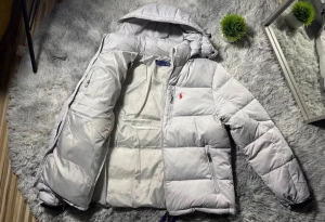 Ljusgrå pufferjacka från Polo Ralph Lauren - Säljer en ljusgrå pufferjacka från Polo Ralph Lauren med huva och två sidofickor med dragkedja. Jackan har det klassiska röda Polo-logot broderat på bröstet och är quiltad för extra värme. Perfekt för kalla dagar och har en clean, modern look.