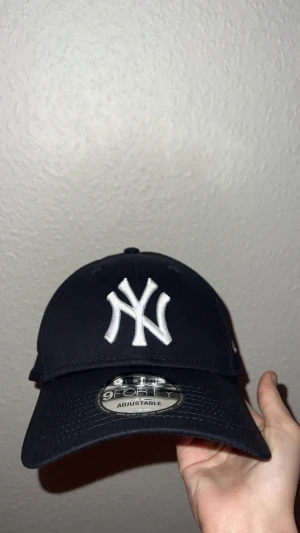 Svart New Era Yankees keps 9FORTY - Snygg svart New Era 9FORTY keps med klassisk New York Yankees-logga i vitt framtill. Justerbar rem med metallspänne baktill och böjd skärm. Tillverkad i 100% bomull för skön passform. Perfekt för dig som gillar sportig streetstyle.            Pris kan diskuteras 