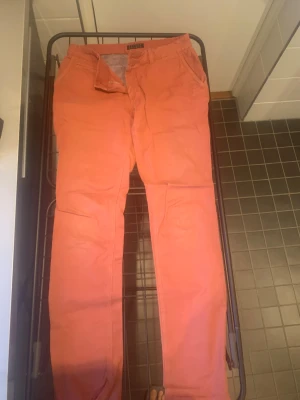 Korallfärgade chinos från Beymen Studio - Snygga korallfärgade chinos från Beymen Studio med klassisk passform och raka ben. Byxorna har framfickor, bakficka med knapp och dragkedja i gylfen. Tillverkade i mjuk bomull som är skön att bära. Perfekt för dig som vill sticka ut med färg.