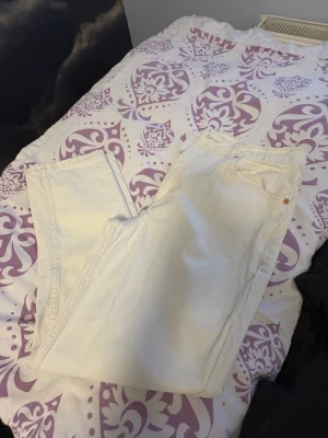 Vita mom jeans från MNG, strl 40 - Säljer ett par vita mom jeans från MNG i storlek 40. Byxorna har klassisk femficksdesign, hög midja och raka ben. Materialet är kraftig bomull med dragkedja och knapp framtill. Perfekt för dig som gillar en chill och trendig look.