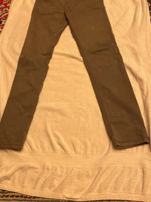 Olivgröna chinos med raka ben - Snygga olivgröna chinos med klassisk rak passform och diskreta bakfickor. Byxorna har en stilren look och är tillverkade i mjukt bomullsmaterial som känns skönt mot huden. Perfekta för dig som gillar enkel och clean stil.