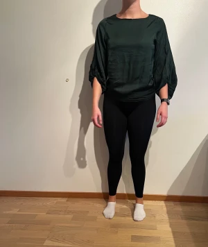 Grön, ”silkig” topp med detaljer vid armarna. Kappahl  - Tvättråd: 30°