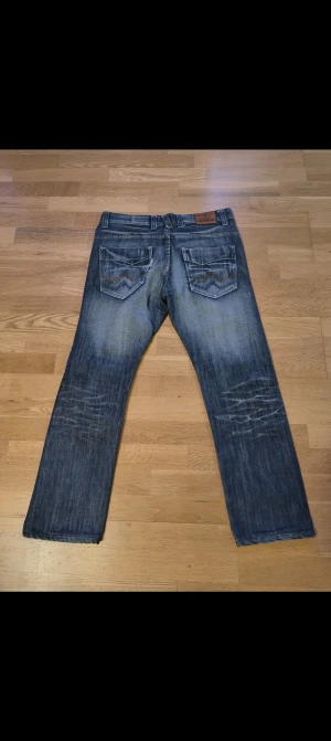Boss  jeans blå straight fit - Snygga boss jeans i blå tvätt med slitningar och raka ben. Klassiska femficksmodellen med coola bakfickor med zigzag-detalj och brunt boss-märke i läder baktill. Jeansen har normal passform och är gjorda i slitstarkt denimtyg.