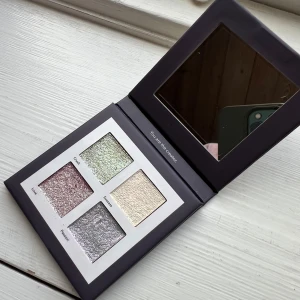 LH cosmetics Shimmer Saga palett - Shimmer Saga palett från LH cosmetics med fyra skimrande nyanser: rosa, grön, silver och champagne. Paletten har spegel i locket och fyrkantiga pans. Perfekt för att skapa glittriga och kreativa looks. Vegansk och dermatologiskt testad. 