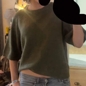 Olivgrön stickad tröja med kort ärm - Olivgrön stickad tröja med ocersized passform och korta ärmar. Knappast andvänd och nytt skick från förra plock andvändaren. Tror den är från H&M då lappen är bort klippt men kan inte säga hundra❤️