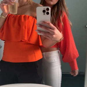  axelbandslös volangtopp - Superfin orange axelbandslös topp med volangdetalj upptill. Använd en gång.