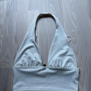 Vit halterneck topp från Divided - Säljer en vit halterneck topp från HM Divided. Toppen har en liten fläck på insidan av ena bysten som troligtvis går bort i tvätten, jag köpte toppen begagnat och inte använt den i min ägo där av vet jag ej säkert om fläcken, skick är jätte svårt att sätta då alla tycker olika men enligt mig är det ett bra skick på toppen då jag är nästan 100% säker att fläcken går bort i tvätten 