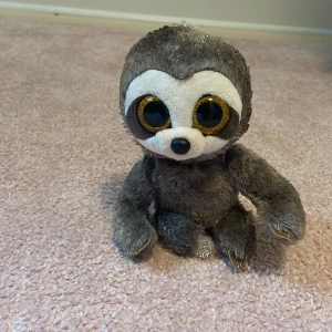 Ty Beanie Boos Dangler - Söt Ty Beanie Boos Dangler gosedjur, föreställande en sengångare med stora glittriga ögon. Mjuk päls och fina detaljer. Märkt med originaletikett. Ser ut att vara i gott skick utan synliga defekter eller slitage.